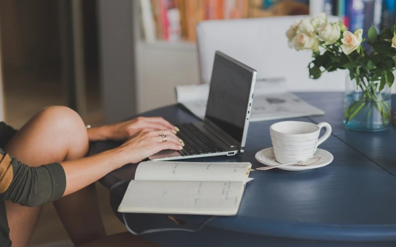 Image showing a laptop on a table with a cup of coffee and a text book